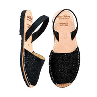 Black glittery sandals with a strap on a white background