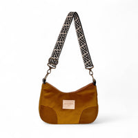 A olive shoulder bag with a patterned black and beige strap, featuring a small beige brand label on the front