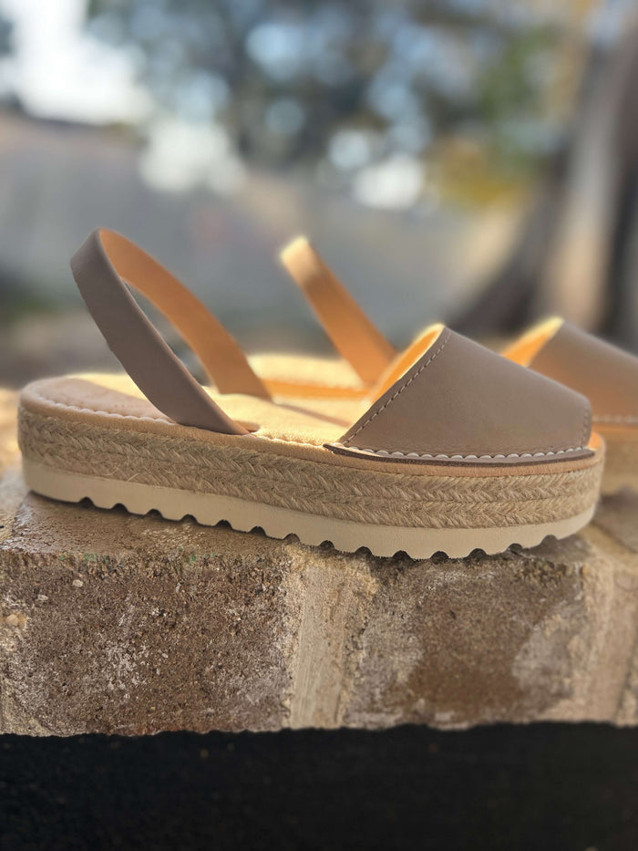 taupe sandals on a stone surface with a blurred natural background