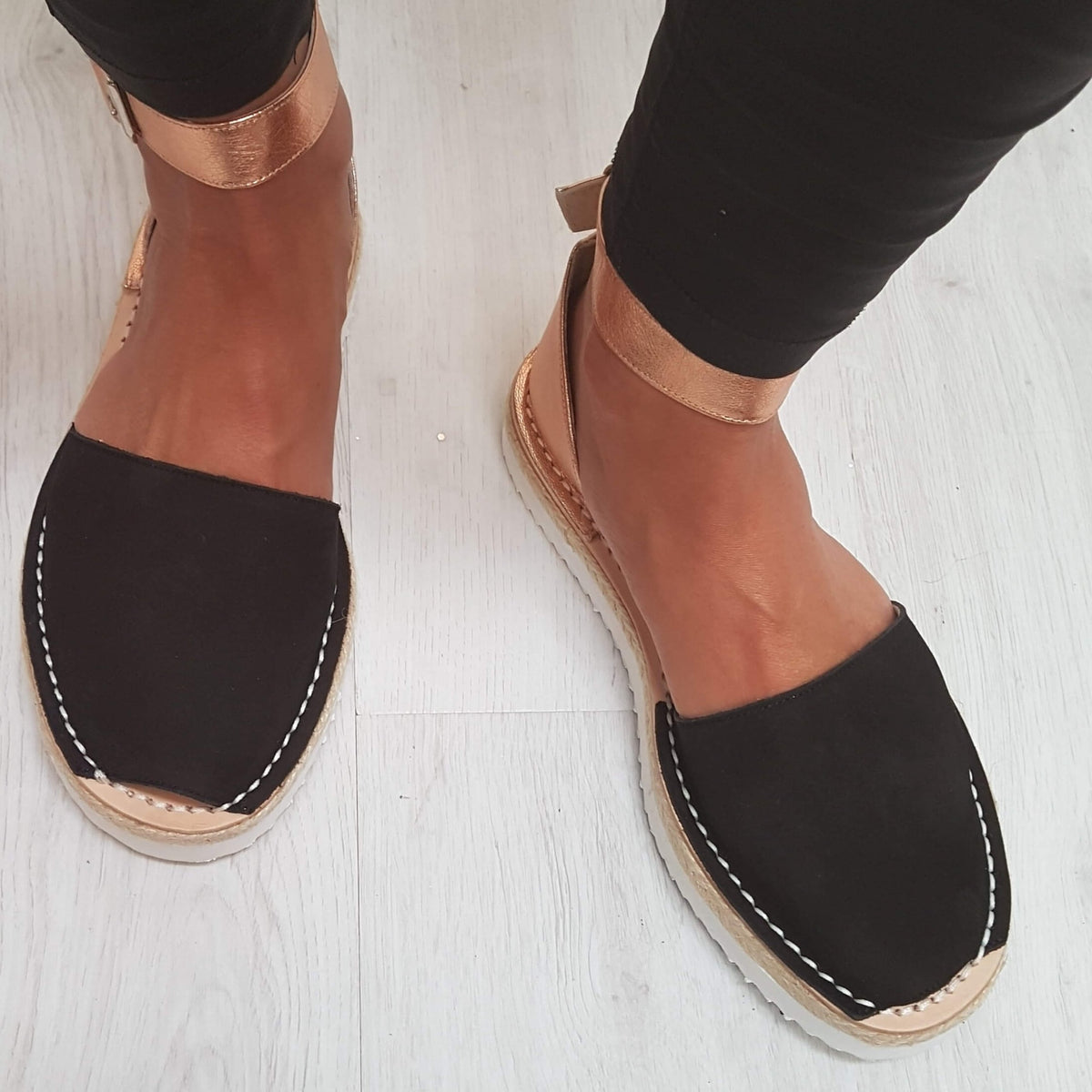 Black espadrilles with white on a light wooden floor