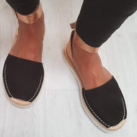 Black espadrilles with white on a light wooden floor