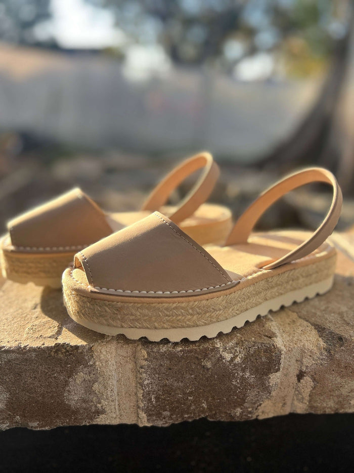 Pair of beige sandals on a stone surface