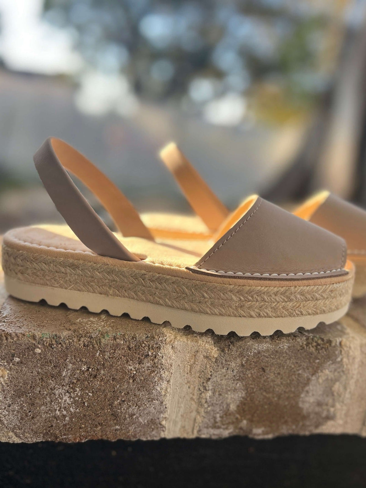 Beige sandals on a stone surface with a blurred natural background