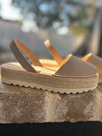 Beige sandals on a stone surface with a blurred natural background