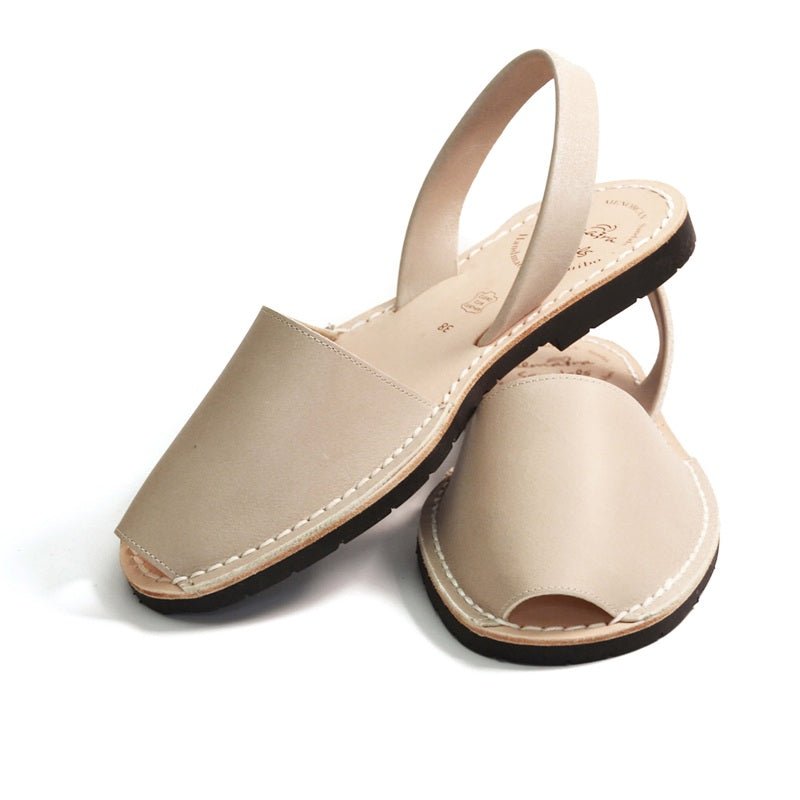 Pair of stone coloured sandals with thin straps on a white background