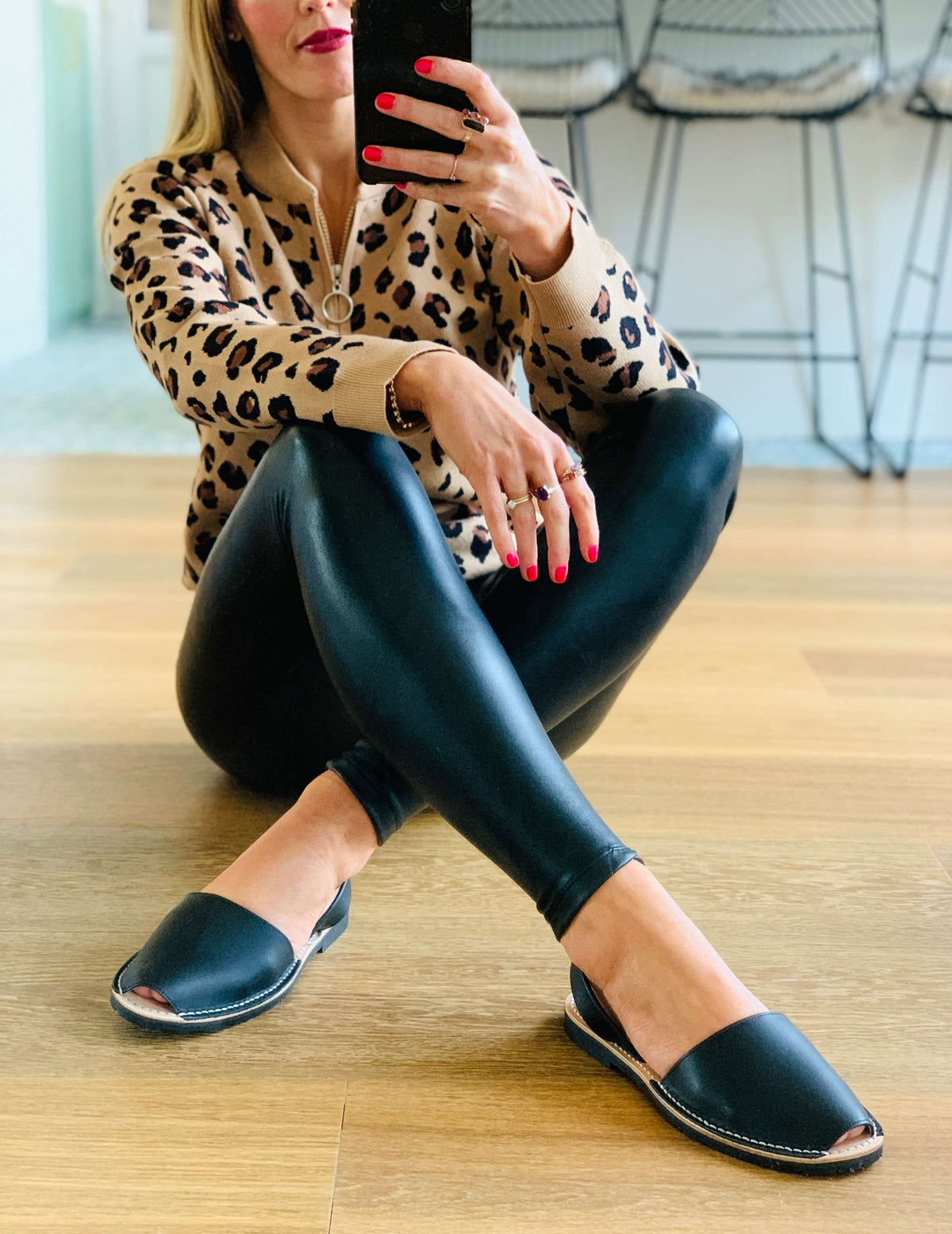 Woman sitting on the floor wearing  black leggings, and black sandals.