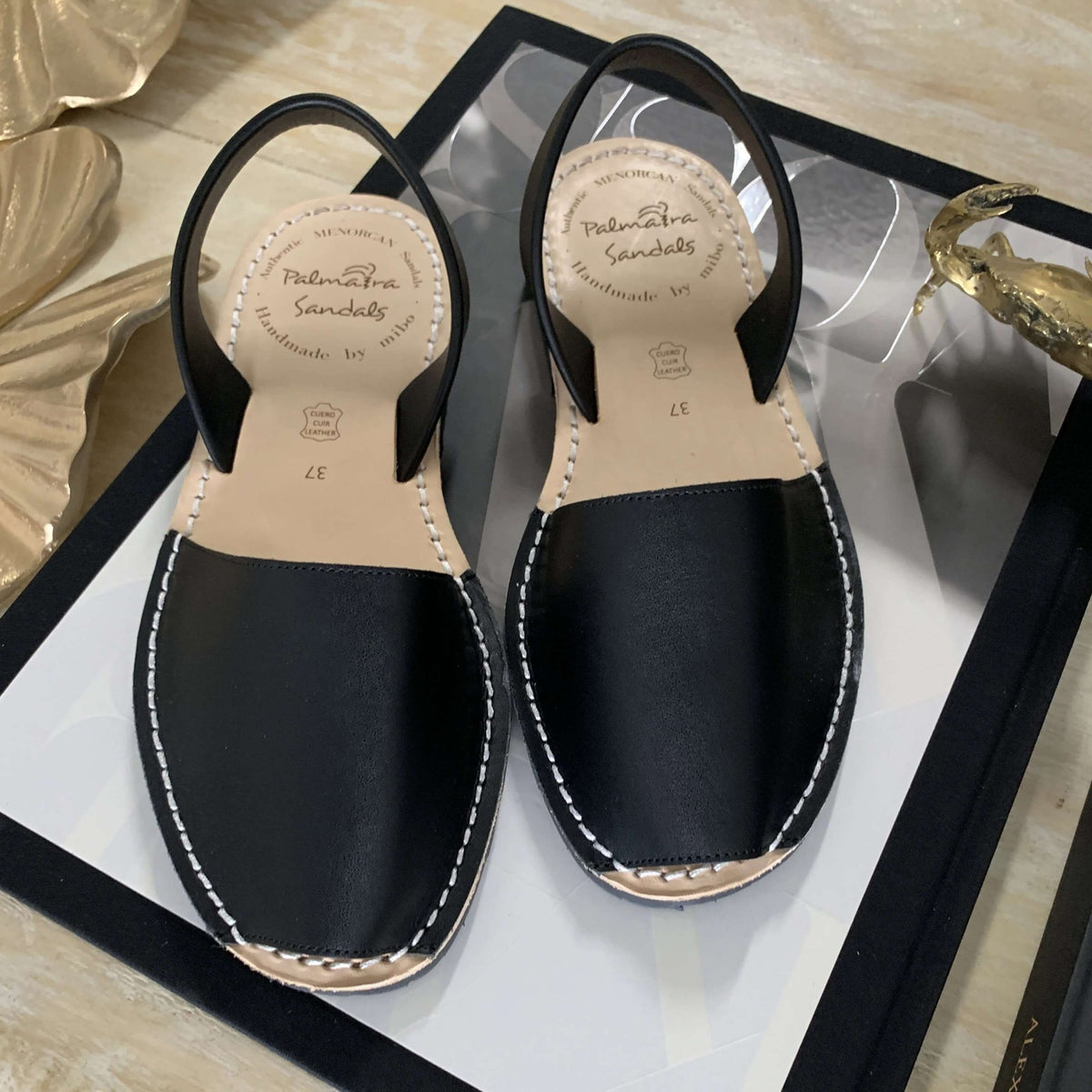 Pair of black sandals on a reflective surface