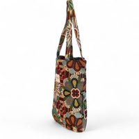 A tall canvas tote bag with a colorful retro floral and geometric pattern, featuring two shoulder straps, shown on a plain white background.