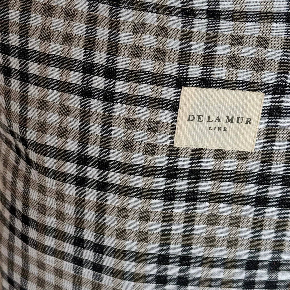 Close-up of a checkered fabric with a 'De La Mur' label.