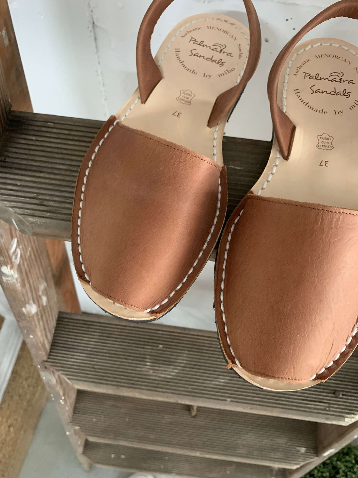 Pair of brown leather sandals on a wooden shelf.