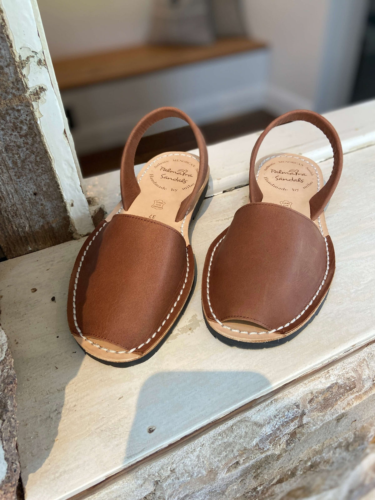 Pair of brown leather sandals on a window ledge