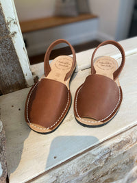 Pair of brown leather sandals on a window ledge