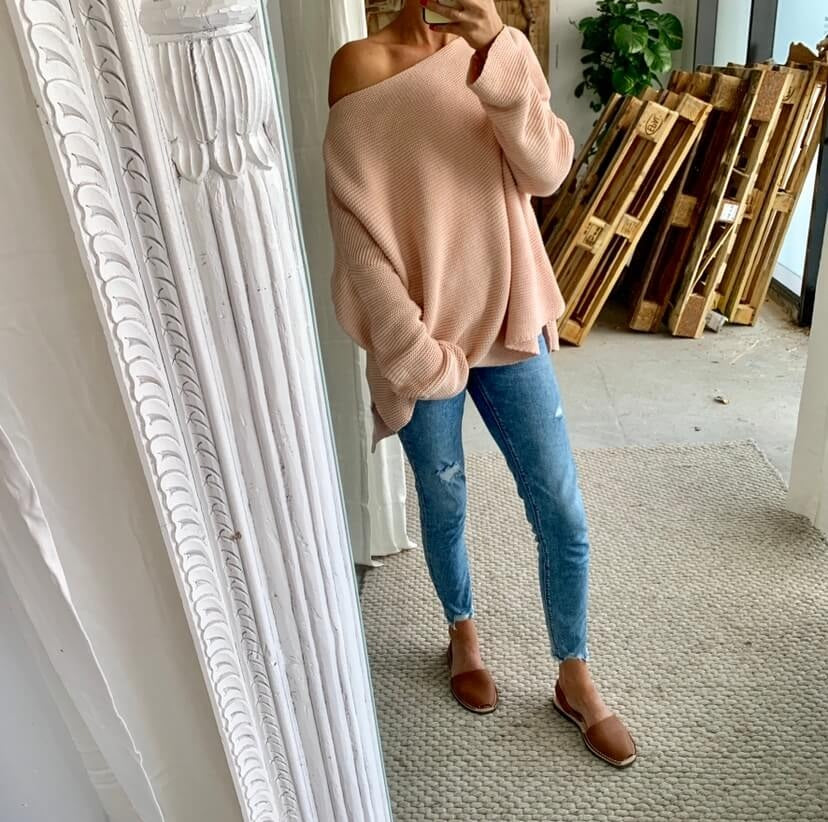 Person wearing brown leather sandals standing in a room with a decorative mirror and wooden pallets.