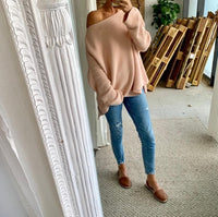 Person wearing brown leather sandals standing in a room with a decorative mirror and wooden pallets.