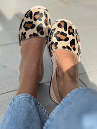 Leopard print flats worn with light blue jeans on a light background