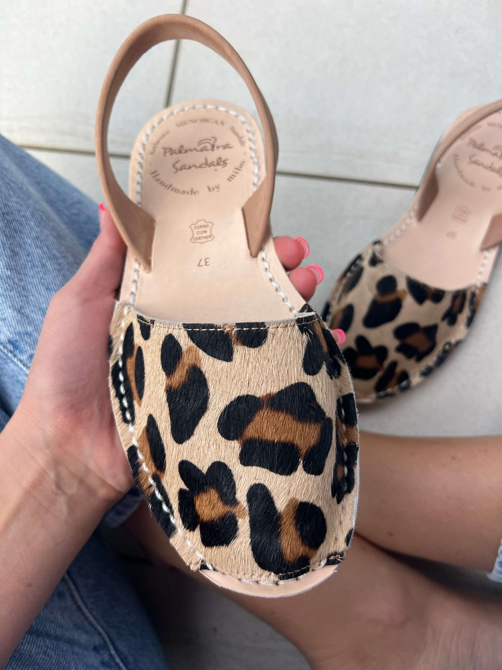 Leopard print sandal held by a hand with a light background