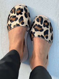 Leopard print avarcas worn on a light blue background