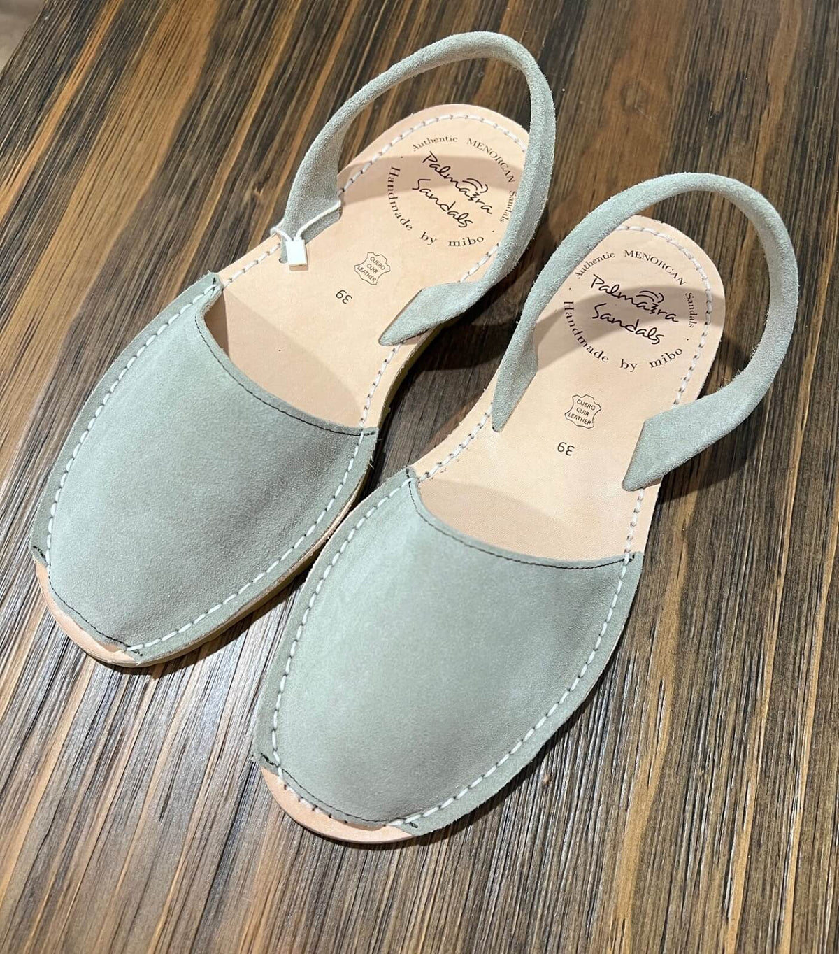 Pair of dusky green sandals on a wooden surface