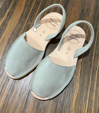 Pair of dusky green sandals on a wooden surface
