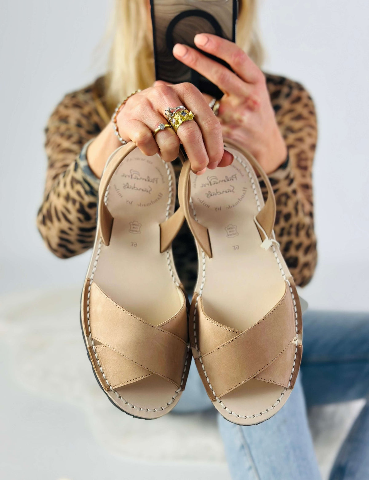 tan sandals held by a person wearing a leopard print top.