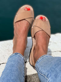 Georgia tan sandals worn with blue jeans against a blurred natural background