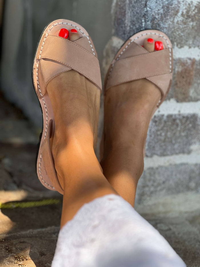 tan nubuck sandals worn on feet with red nail polish, standing on a stone surface.