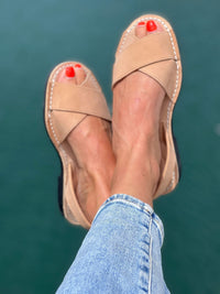 Tan sandals worn with blue jeans against a teal background