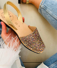 Glittery sandal held by a hand with a blurred background