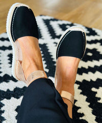 Black espadrilles worn on a patterned rug.
