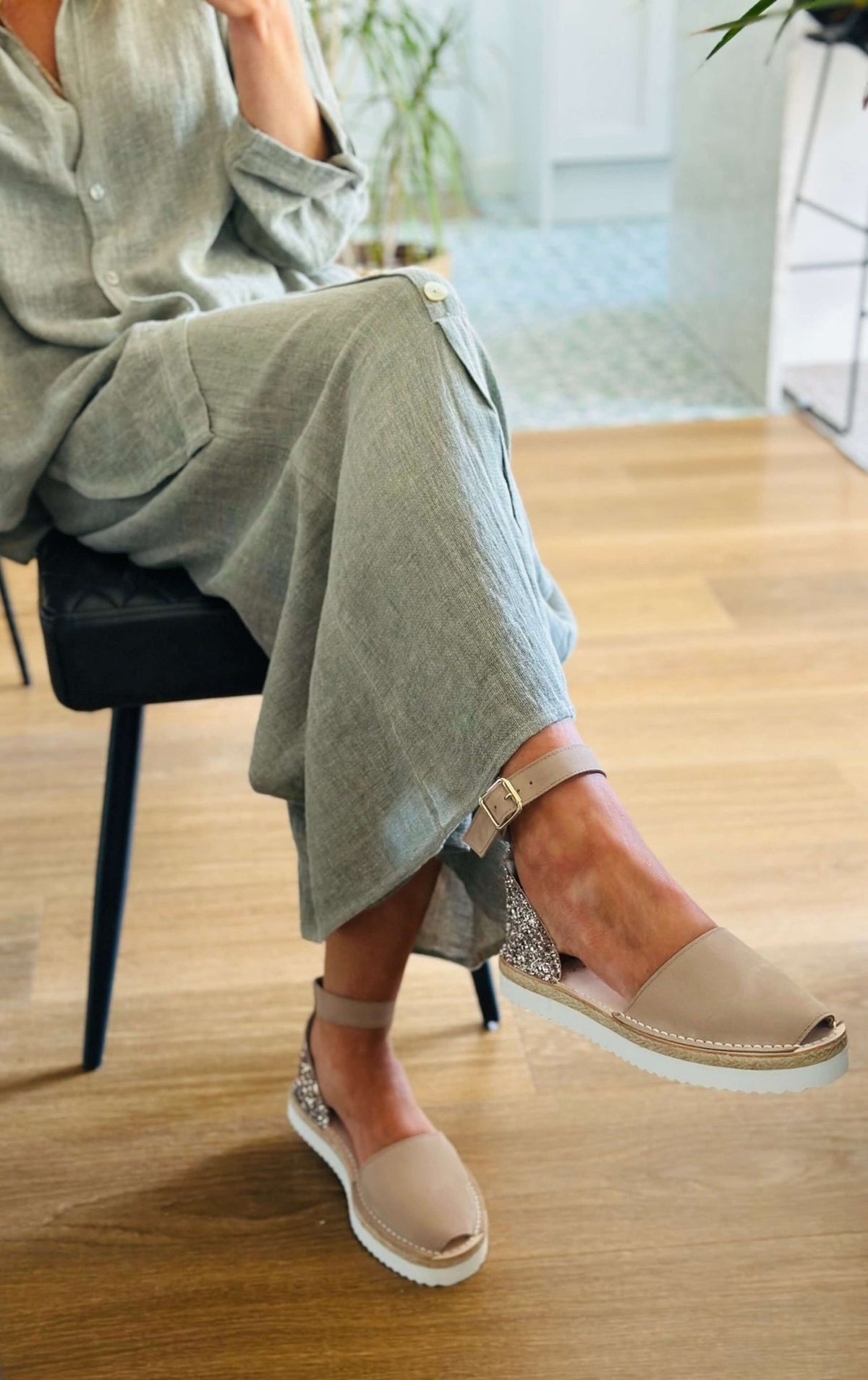 Person wearing taupe sandals on a wooden floor