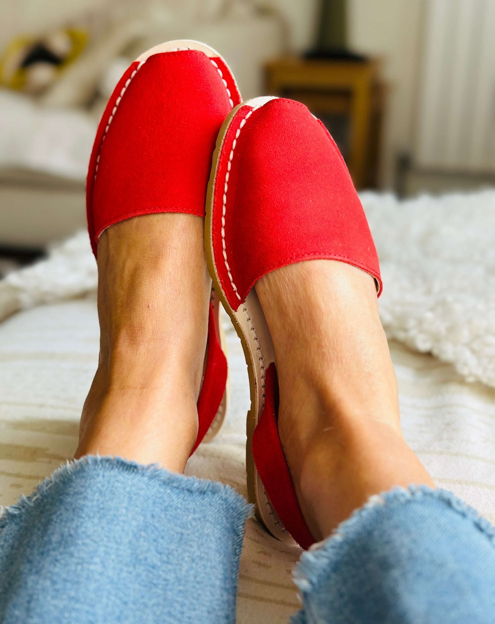 Red shoes being worn on a bed with a blurred background