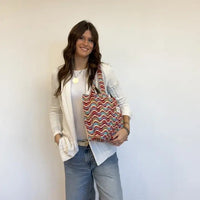 Woman holding a colorful patterned bag against a plain background