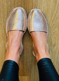 Silver metallic espadrille sandals worn on a wooden floor