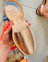 Rose Gold sandal with 'Palmaira Sandals' branding held by a person.