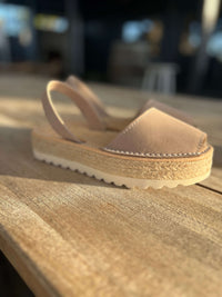 Beige sandal with a textured sole on a wooden surface