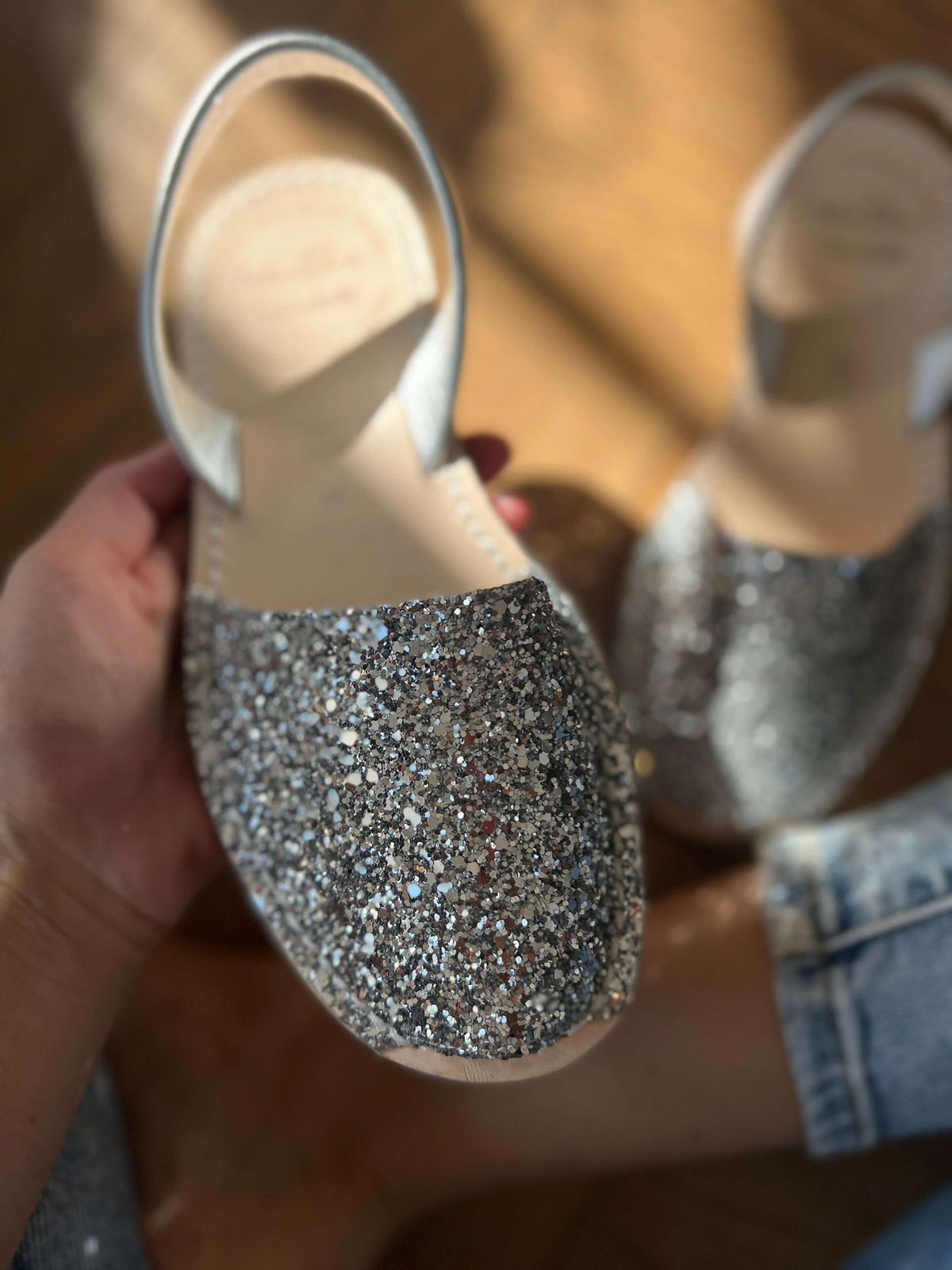 Silver glittery shoes held by a person with a blurred background