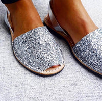 Silver glittery open-toe sandals on a textured surface