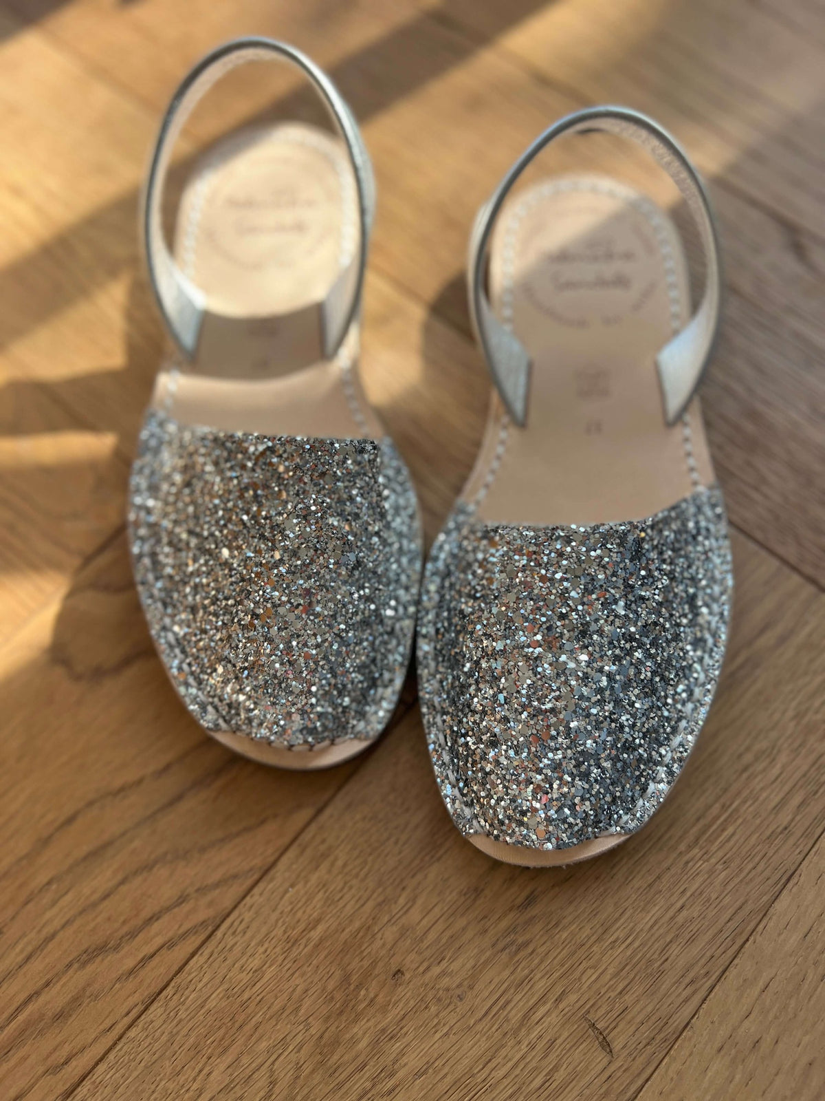 Pair of glittery silver shoes on a wooden floor