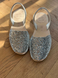 Pair of glittery silver shoes on a wooden floor