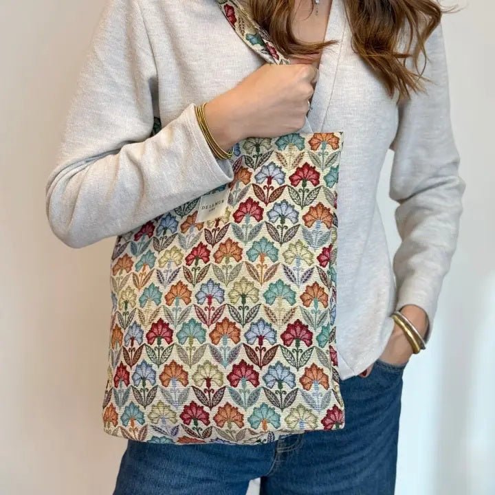 Person holding a colorful floral-patterned bag against a plain background