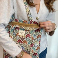 Person wearing a floral apron over a white shirt with a visible brand name.