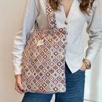 Person holding a patterned tote bag with a neutral background