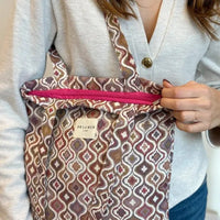 Person holding a patterned bag with a visible brand label.