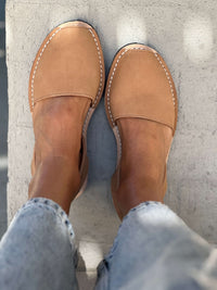 Tan nubuck leather shoes worn with light blue jeans on a concrete floor.
