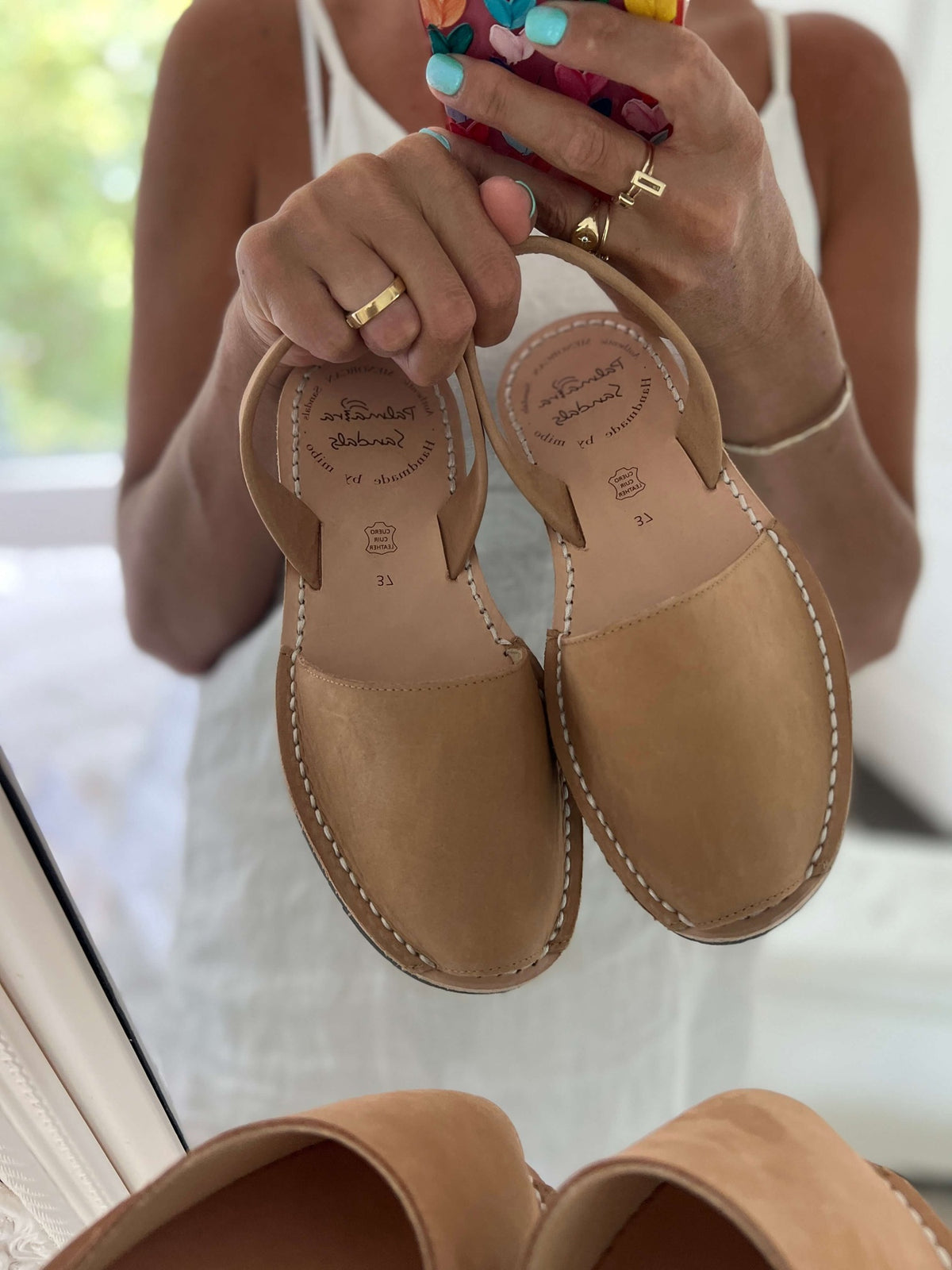 Pair of tan sandals held by a person.