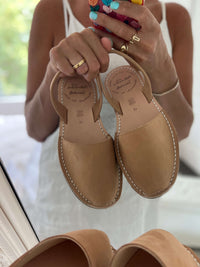 Pair of tan sandals held by a person.
