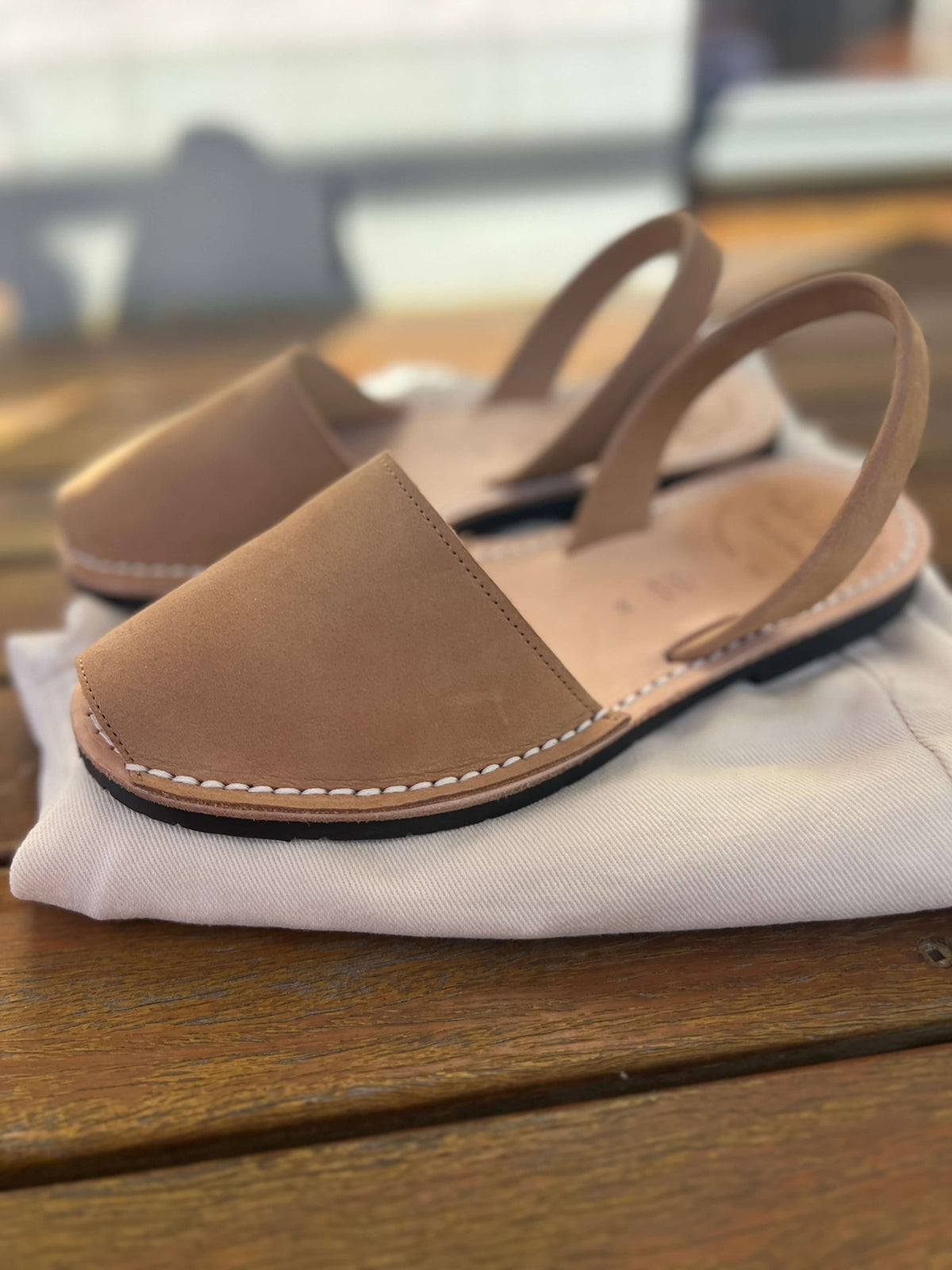Pair of tan nubuck sandals on a white pair of jeans.