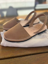 Pair of tan nubuck sandals on a white pair of jeans.