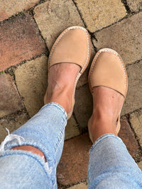 Tan avarcas worn with light blue jeans on a brick pavement