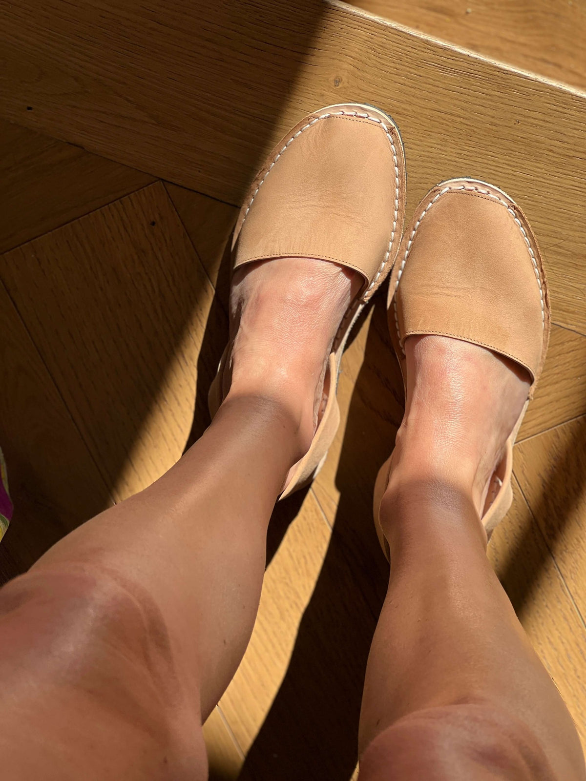Tan sandals worn on a wooden floor
